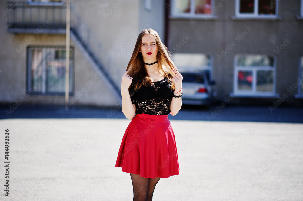 Portrait of girl with black choker necklace on her neck and red leather skirt at street of city.