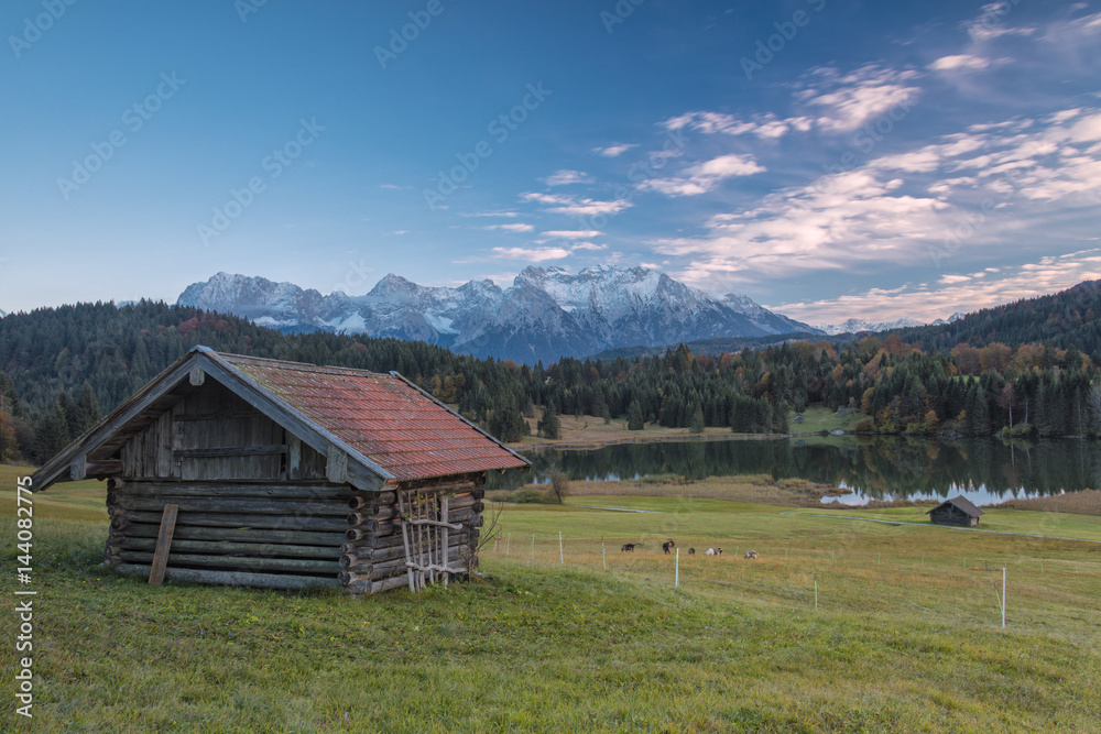 Wooden hut frames the alpine lake surrounded by the Alps, Geroldsee, Krun, Garmisch Partenkirchen, Upper Bavaria, Germany Wooden hut frames the alpine lake surrounded by the Alps, Geroldsee, Krun, Garmisch Partenkirchen, Upper Bavaria, Germany