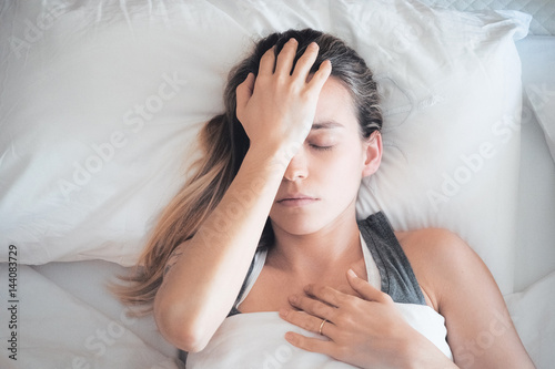 Donna con mal di testa a letto, emicrania e sinusite  photo