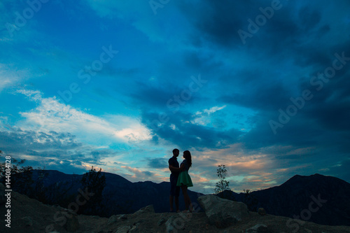 Silhouette of the newlyweds against the sky at sunset. Wedding in Montenegro. Silhouette of a couple. Silhouette of the bride and groom.