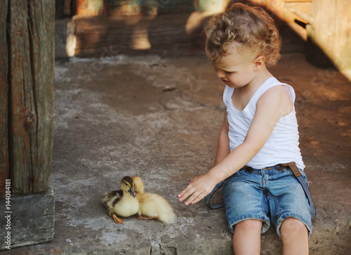 boy with little yellow duckling in summer village