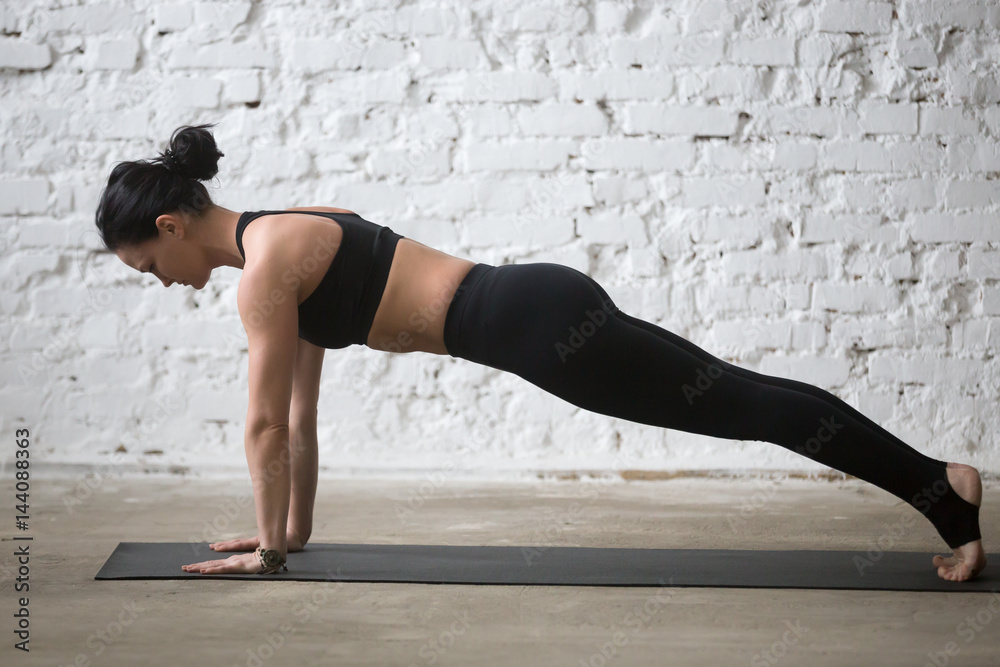 Middle aged yogi attractive woman practicing yoga concept, standing in Push ups, press ups exercise, phalankasana, Plank pose, working out wearing black sportswear, full length, white loft background