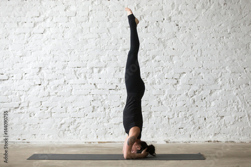 Photography Young yogi attractive woman practicing yoga concept, standing in salamba sirsasa