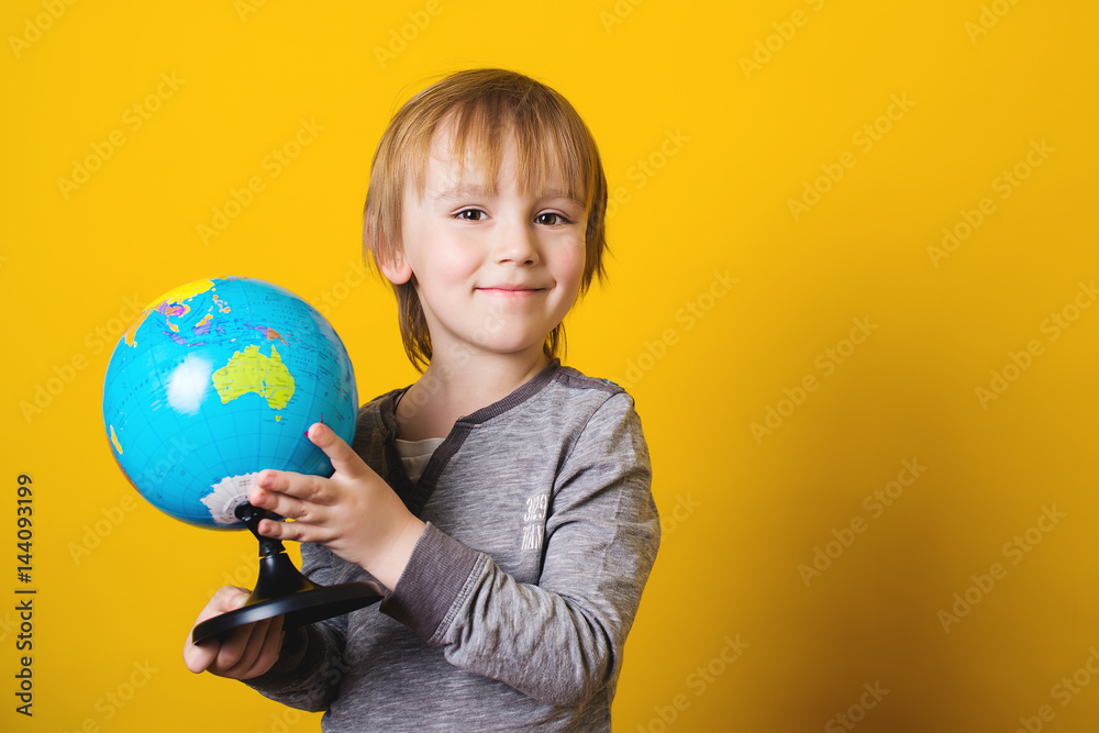 Smiling little boy holding globe in hands - isolated on yellow. Smiling little boy holding globe in hands - isolated on yellow.