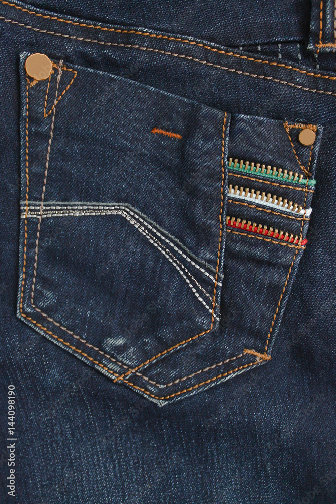 Fototapeta premium Texture fragment of denim with bright seams of thin fabric and a large pocket. The background image on the production of rigid denim clothing
