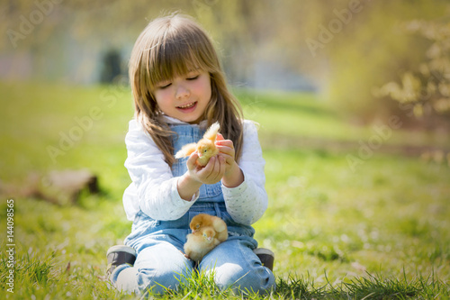 Young beautiful girl, playing with little newborn chick in the park