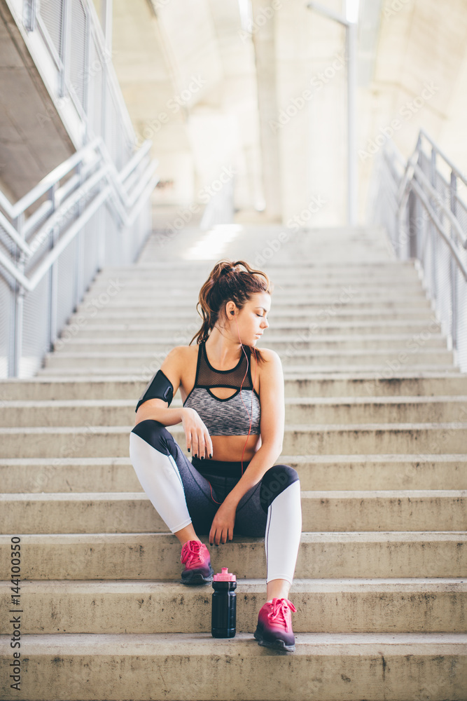 Sports woman sitting on the stairs and relaxing 
 