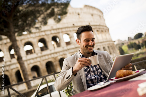 Photography oung man sitting and having a cup of coffee in Rome, Italy