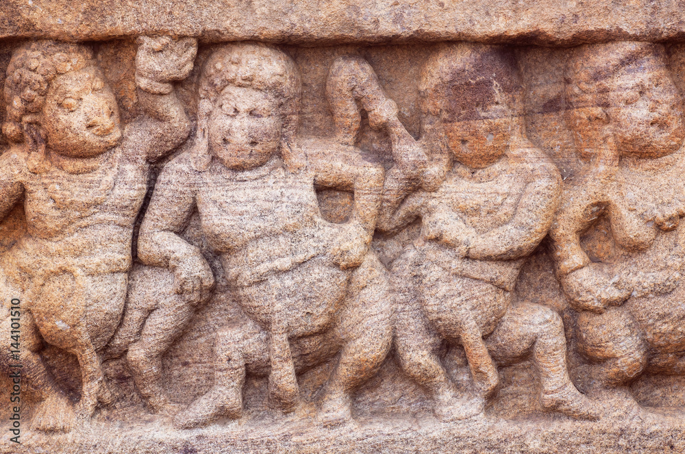 Dancing overweight people on stone relief of 7th century temple in Badami town, India. Famous for rock cut architecture of Karnataka