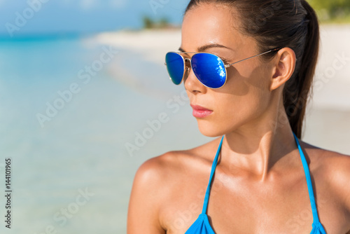 Blue mirror aviator sunglasses sexy woman beauty. Beach bikini Asian model wearing fashion eyewear trendy mirrored glasses and turquoise swimwear looking at the ocean.