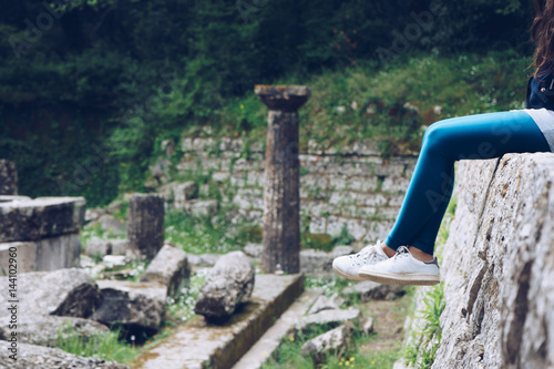 Girl is sitting on remains of a Doric temple, Mon Repos park, Corfu Town, Greece