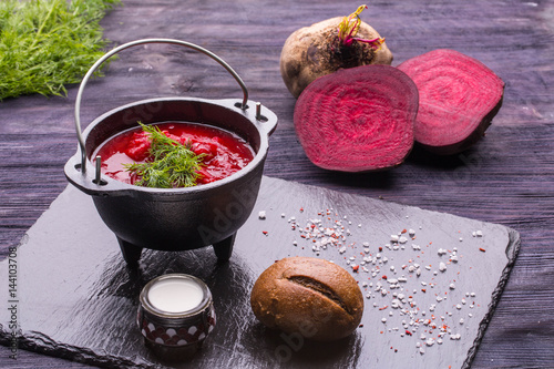  Borsch with a beetroot and greens, sour cream and spices in a pig-iron kettle