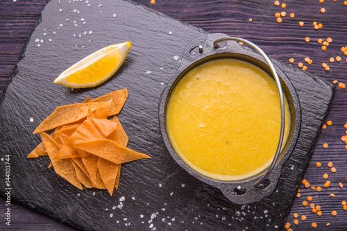 Lentil soup with toasts and a lemon, is served in a pig-iron kettle