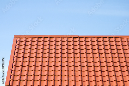 Red roof of metal roofing on the sky background