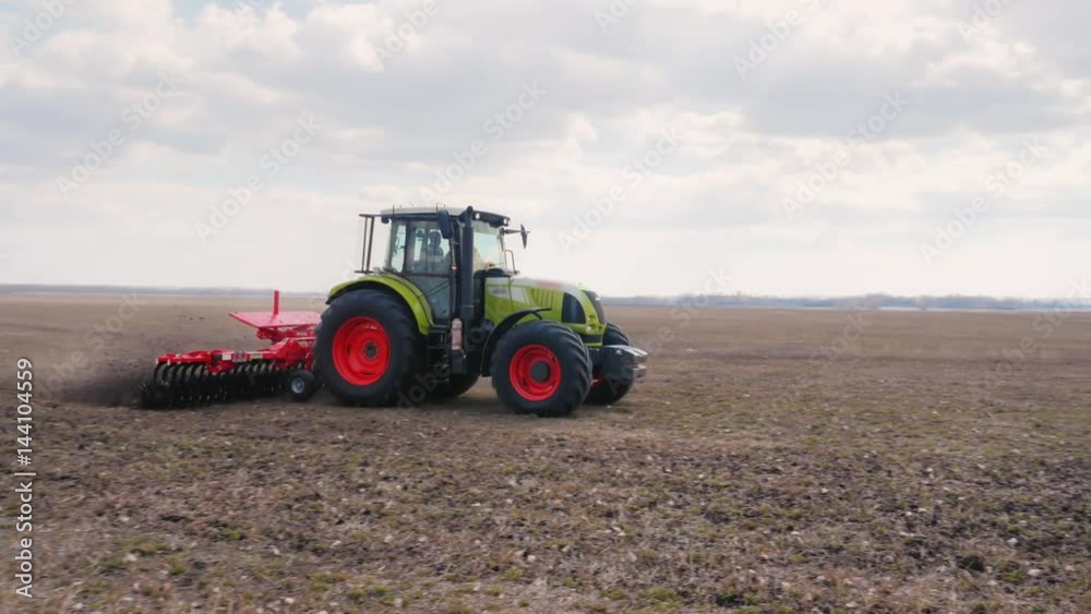 Steadicam fly around shot: The tractor plows the land on the field. Agribusiness is modern Steadicam fly around shot: The tractor plows the land on the field. Agribusiness is modern