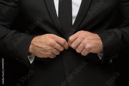 Serious handsome businessman in a suit on black background
