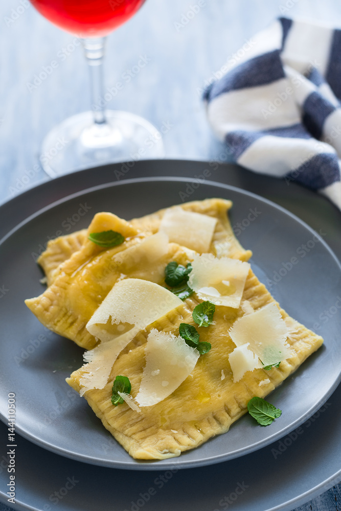 Homemade ravioli with spinach and ricotta cheese with grated parmesan on blue plate. Selective focus Homemade ravioli with spinach and ricotta cheese with grated parmesan on blue plate. Selective focus