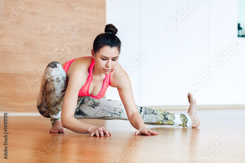 young woman stretching and warming up before working out at a yoga photo