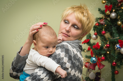 Mother hugging her baby by the Christmas tree