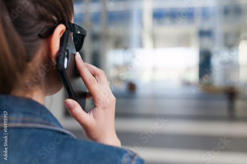 Woman talking on smartphone, back view, with space for text or design concepts.