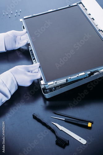 Process of computer repair. Engineer in white gloves disassembling computer.
