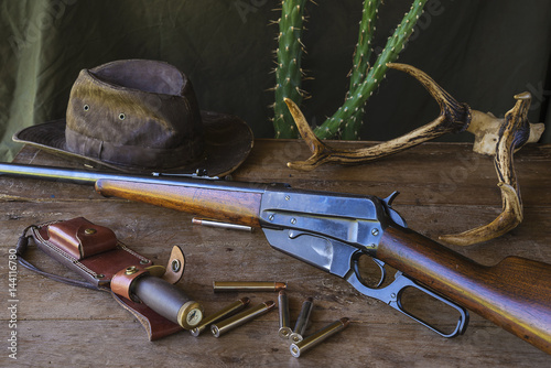 western still life. american hunting carbine and hunting ammunition on old wooden table