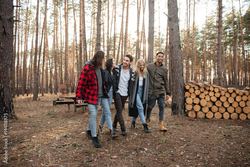 Happy group of friends walking outdoors in the forest.
