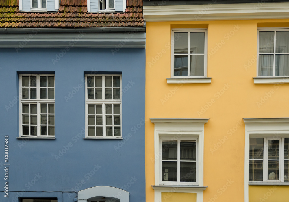 Two neighboring old houses. The houses are painted in yellow and blue colors. City of Riga. Latvia.