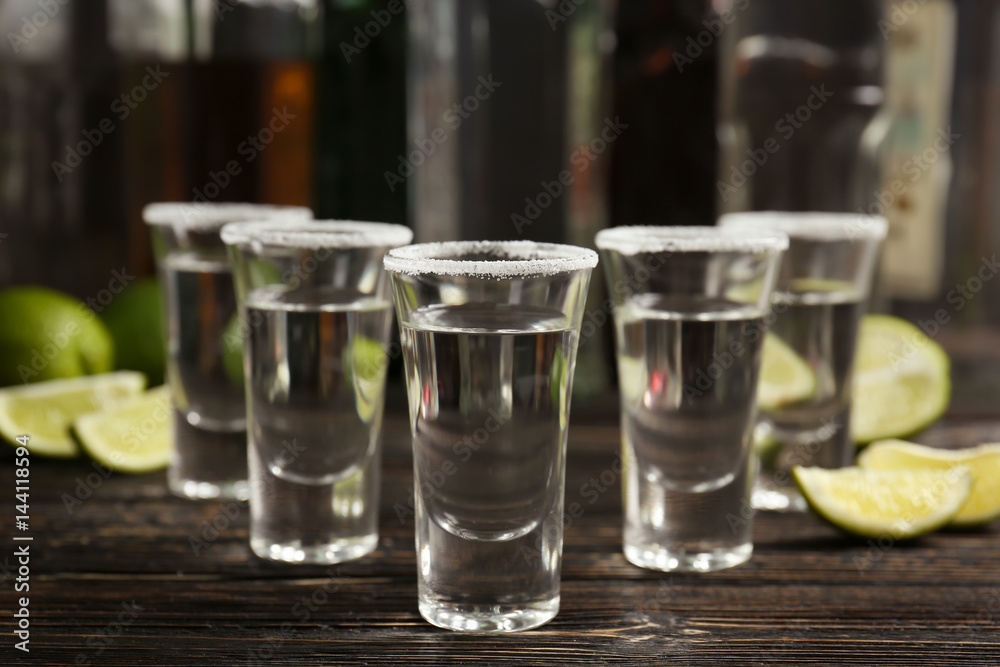 Tequila shots with lime slices and salt on table Tequila shots with lime slices and salt on table