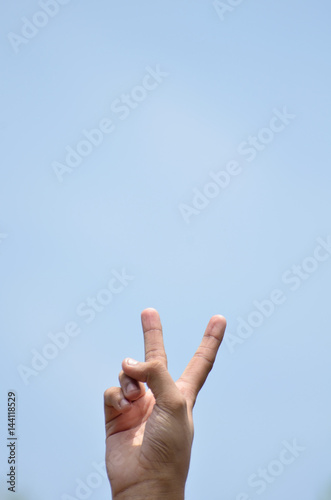 Victory symbol insky background by human hand photo