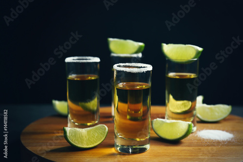 Tequila shots with lime slices and salt on table