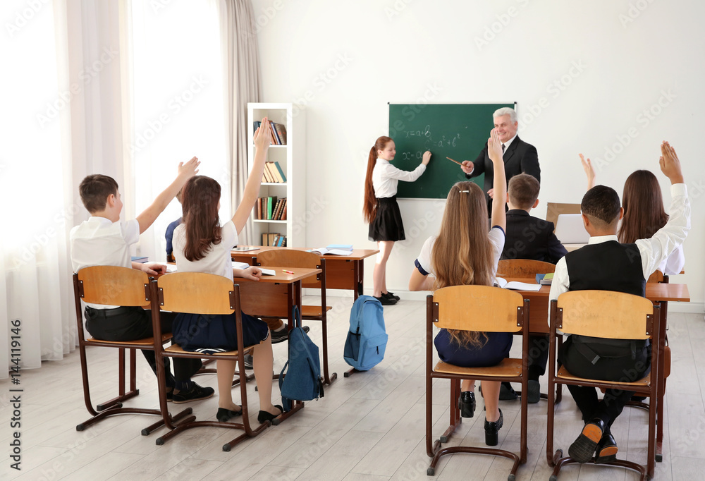 Pupils raising hands to answer at lesson in classroom Pupils raising hands to answer at lesson in classroom