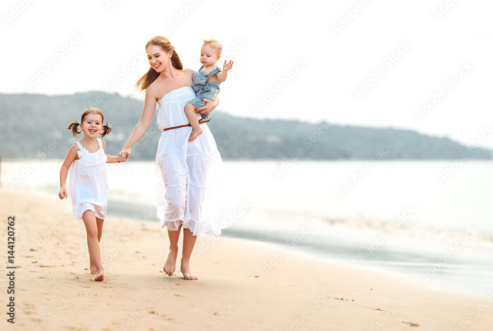 Happy family mother and children on beach by sea in summer Happy family mother and children on beach by sea in summer