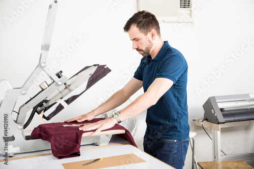 Photography Man using a serigraphy press on a shirt