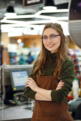 Happy cashier woman on workspace in supermarket shop