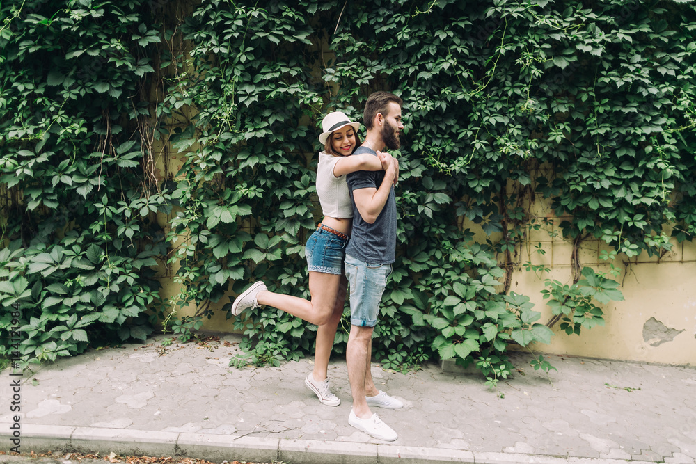 Young and stylish couple walking on the street of summer. Bearded boy and fashionable girl are loving and flirting. Young and stylish couple walking on the street of summer. Bearded boy and fashionable girl are loving and flirting.