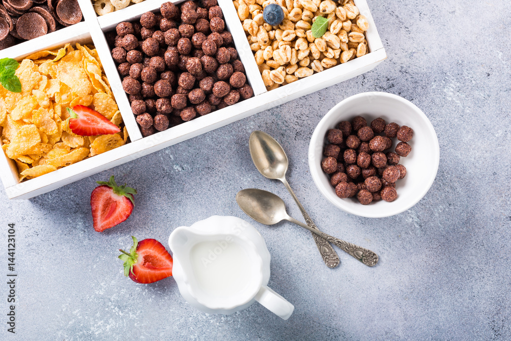 Variety of cold quick breakfast cereals with berries in white wooden box, healthy eating for kids, overhead shot Variety of cold quick breakfast cereals with berries in white wooden box, healthy eating for kids, overhead shot
