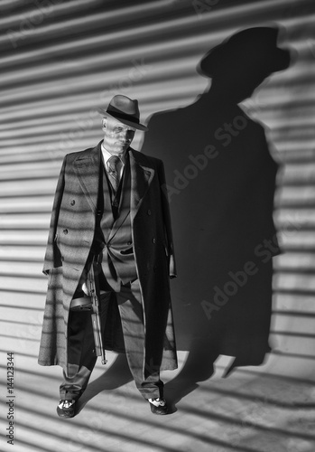 Tableau sur toile Black and white image of a mature man dressed as a 1940s gangster, on a grey bac