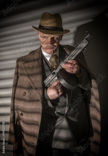  1940s male gangster holding a machine gun