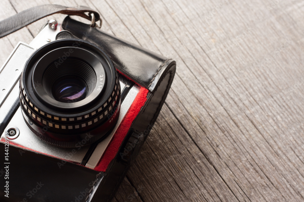 Vintage camera from 1970s on a wooden background with copy space