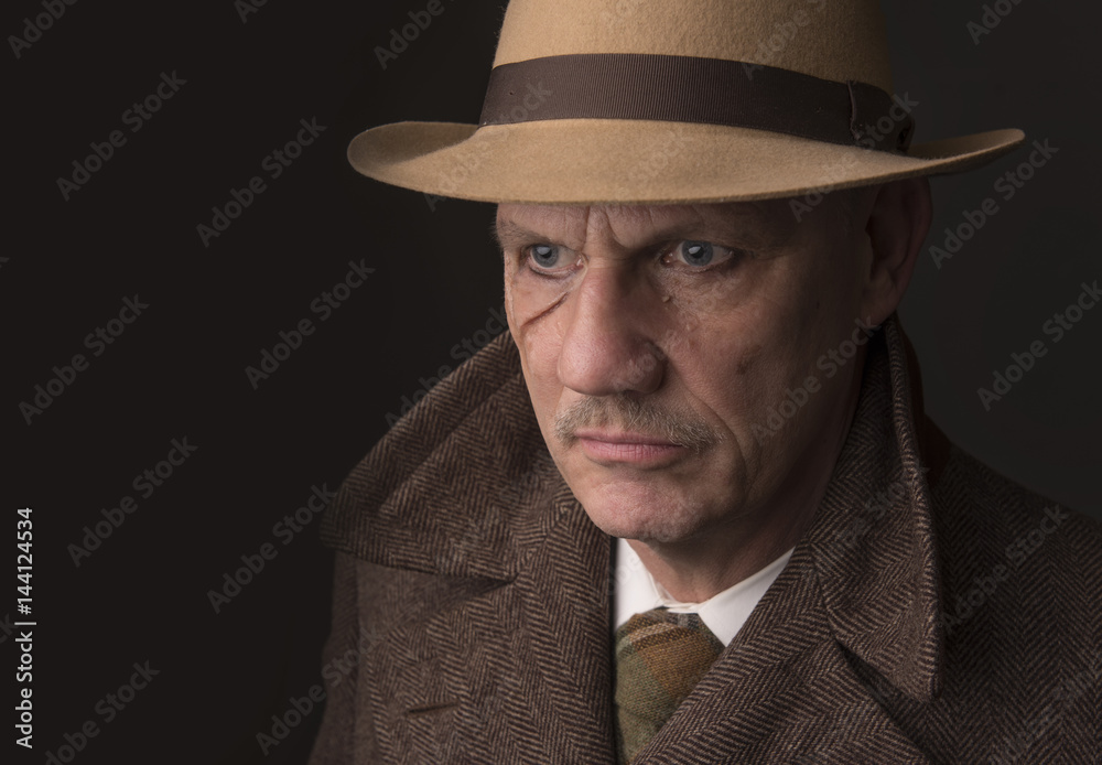 Mature man dressed as a 1940s gangster, on a grey background, taken with copy space 