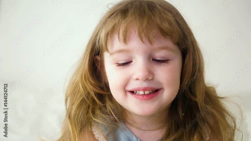 redhead girl with long hair two years smiling at the camera sitting on white bed redhead girl with long hair two years smiling at the camera sitting on white bed