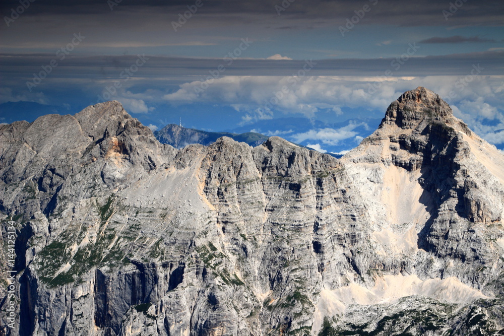 Peaks of Prisojnik (or Prisank, left) and Razor (right), between them Dobratsch with radio tower, Gailtal Alps, Austria, in cloud layers, from Kanjavec, Julian Alps, Triglav National Park, Slovenia