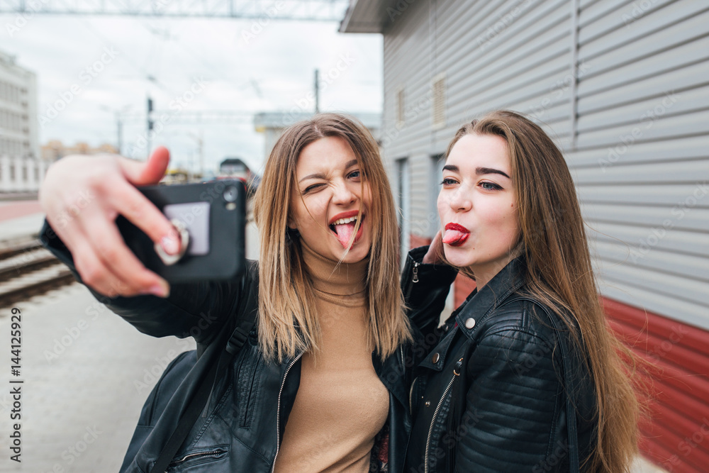 Two young girls taking selfie using smartphone Two young girls taking selfie using smartphone