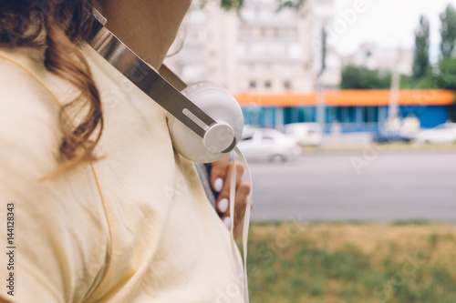 Closeup of woman with headphones goes around the city in the summer