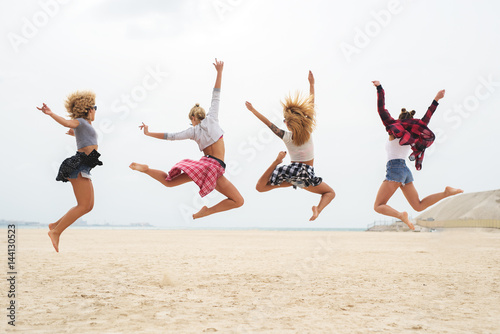 Young women in summer fashion outfit jumping in water.