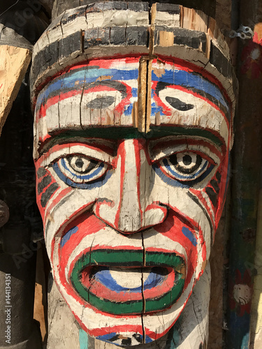 Authentic painted wooden totem pole in an African village. Original sculpture in wood. Wood tribal sculpture, colored portrait. 