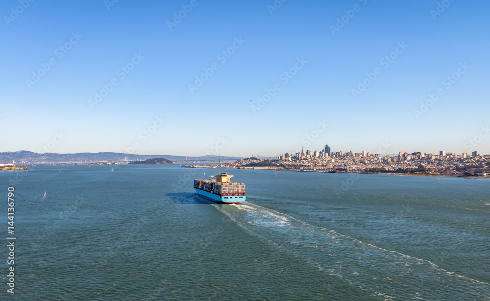 Container Cargo Ship entering San Francisco Bay and downtown skyline - San Francisco, California, USA