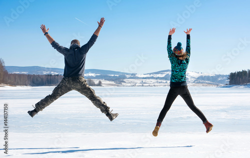 Happy friends jumping on frozen lake