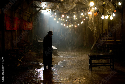 Man in black hat in the rain at dark overcast street